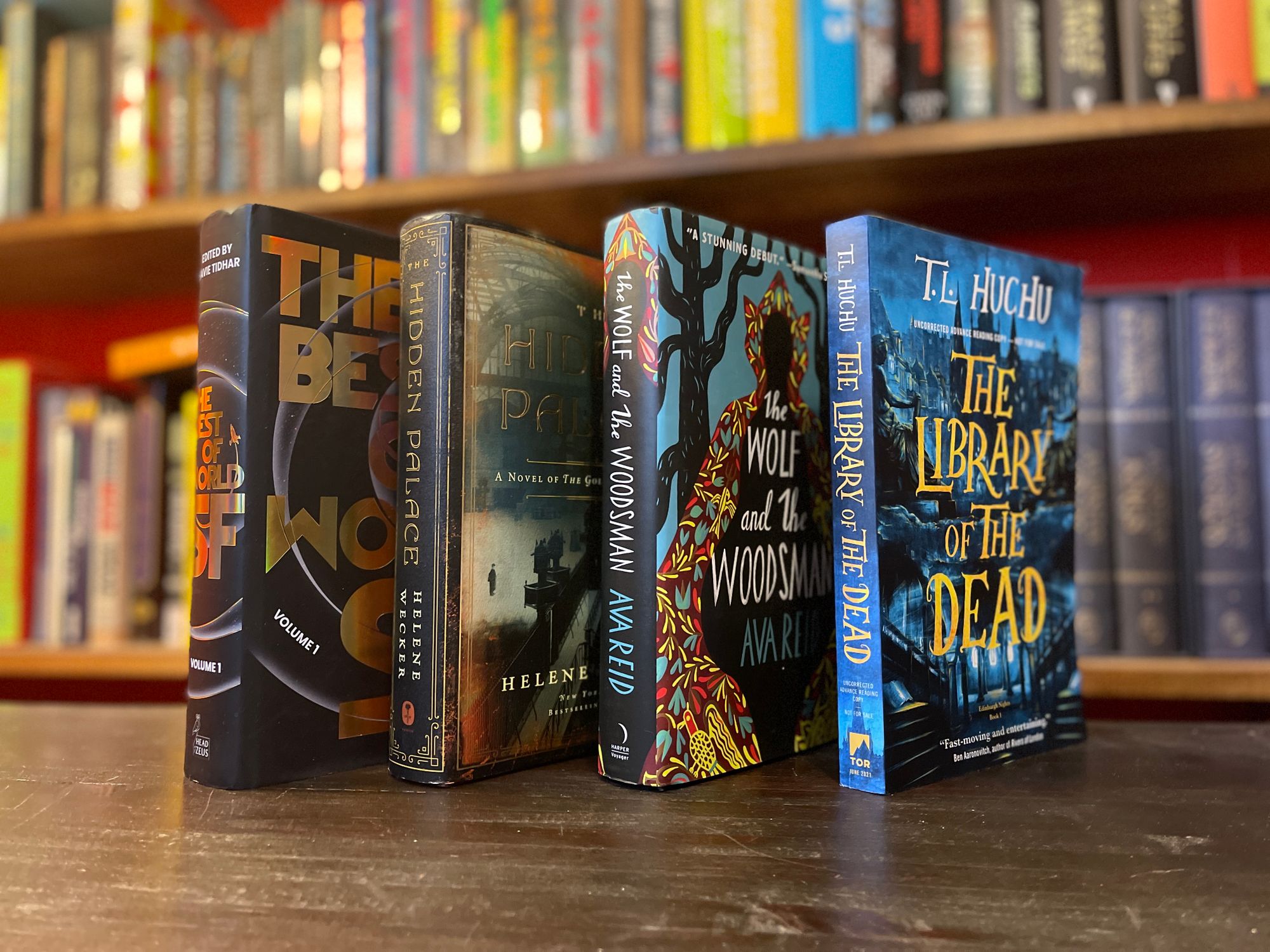 Four books standing up at an angle with a bookshelf in the background.